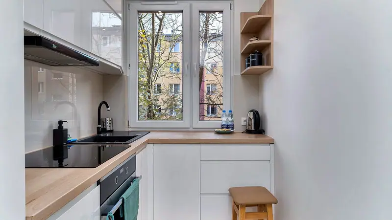 Small white galley kitchen with wood countertops and a window