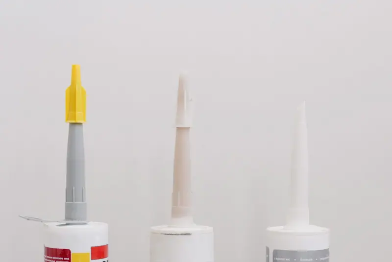 Tubes of caulk and sealant lined up on a white surface