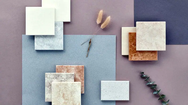 Stone and quartz tile samples laid out on colored paper