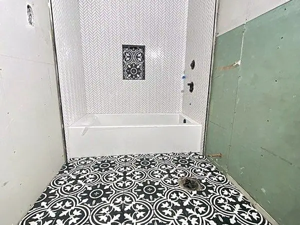 New shower with white tile walls, a patterned niche and a black-and-white patterned floor